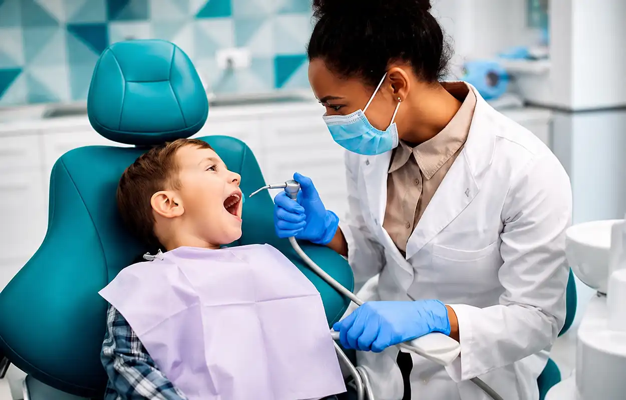Dentista realizando atendimento odontológico em criança em consultório moderno, com equipamentos profissionais e foco em saúde bucal preventiva.